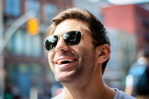Happy man wearing sunglasses and smiling under the sun